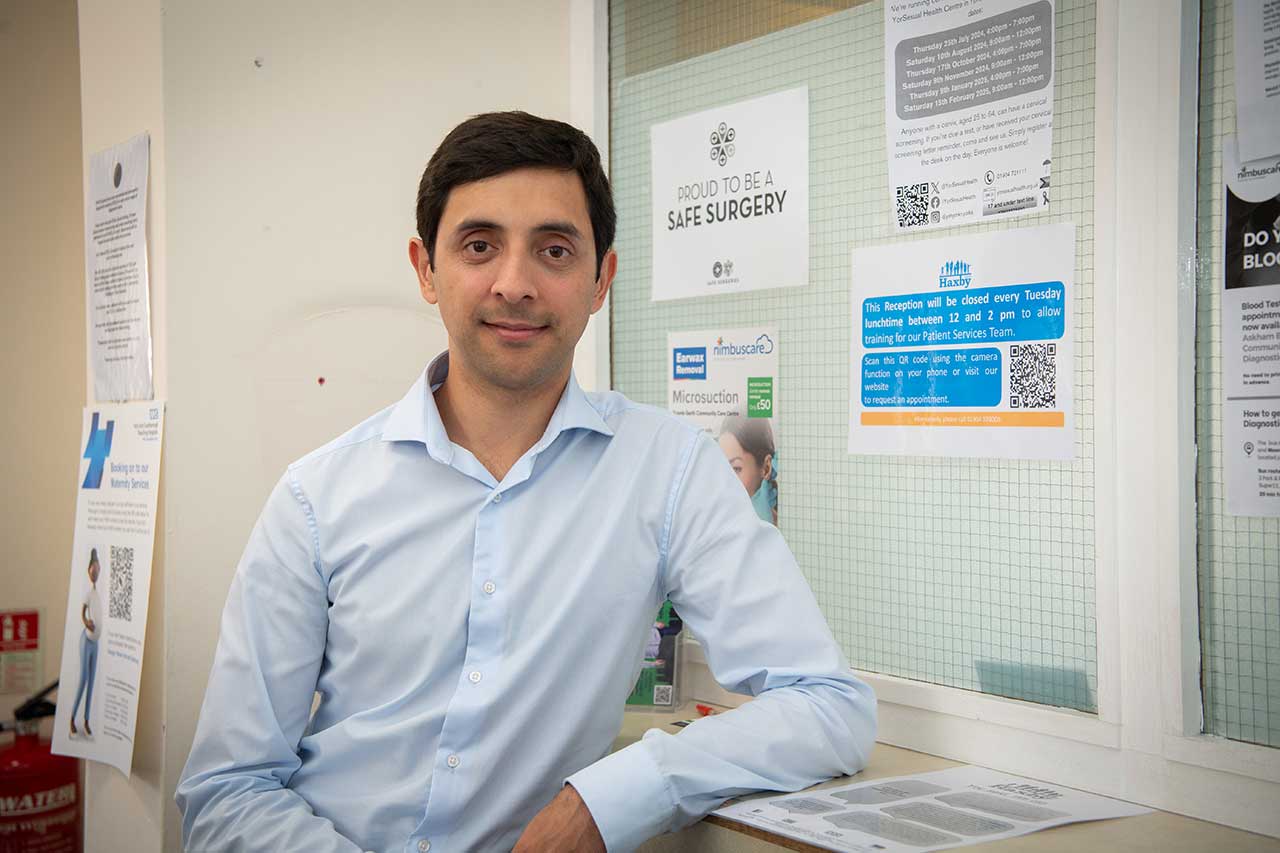 Dr Thomas Patel-Campbell leans against the reception counter in Gale Farm Surgery.