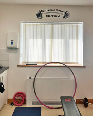 A portrait image of a section of the Barrowland Surgery staff gym, with white walls and gym equipment.