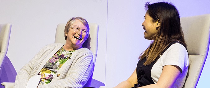 An older and younger woman sitting down and laughing together