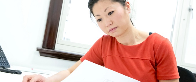 A woman in a red top reading from a piece of paper