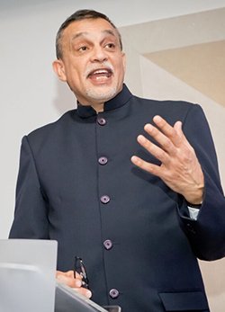 A small card image of Dr Aneez Esmail speaking at a lectern.