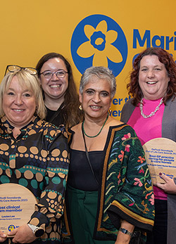 Professor Kamila Hawthorne stands with Daffodil Standards award winners with their wooden trophies.