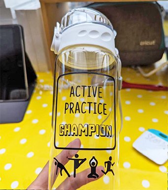 A hand holds a clear water bottle with 'Active Practice Champion' branding. 