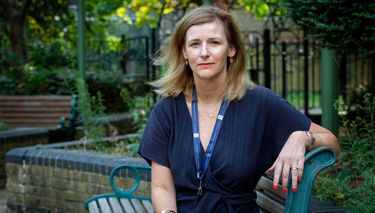 Dr Emma Ryan sits on a park bench with her left arm rested on the backrest.