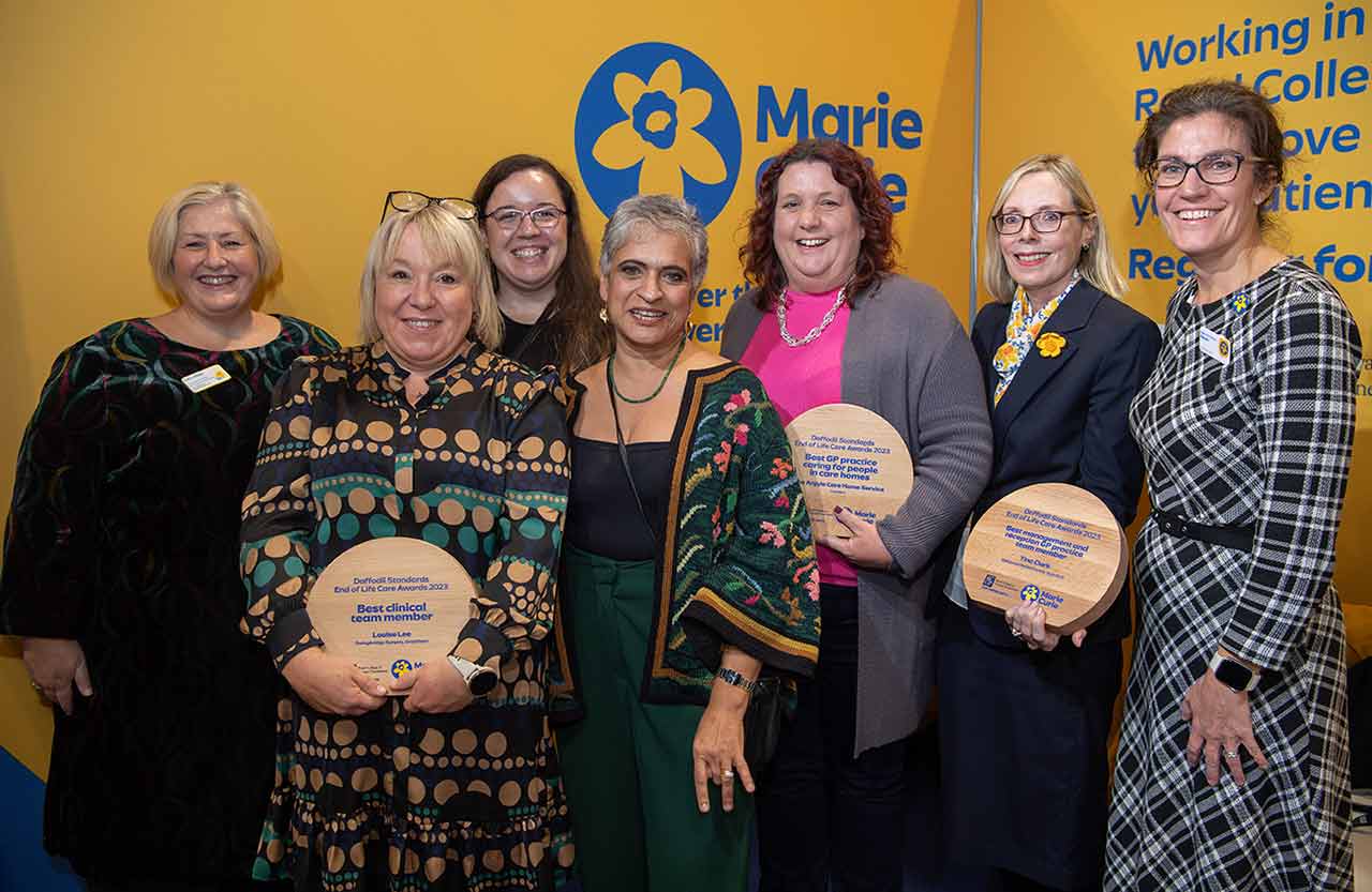 Professor Kamila Hawthorne stands with Daffodil Standards award winners with their wooden trophies.