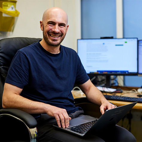 Dr Benjamin Brown sits at a desk with his laptop computer.