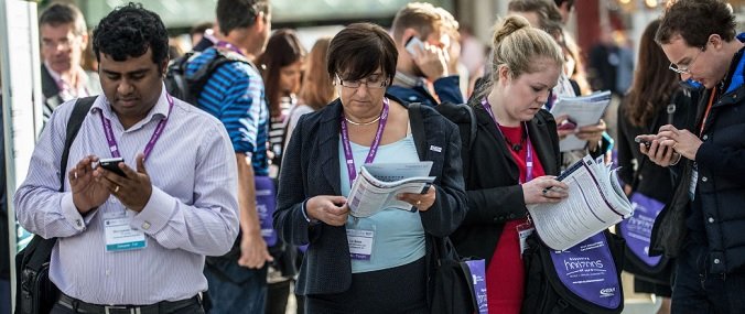 A group of people at an RCGP event on their phones and looking at brochures