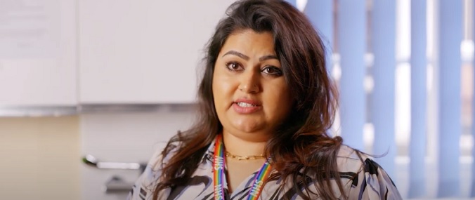 A woman with long hair speaking to someone off-camera