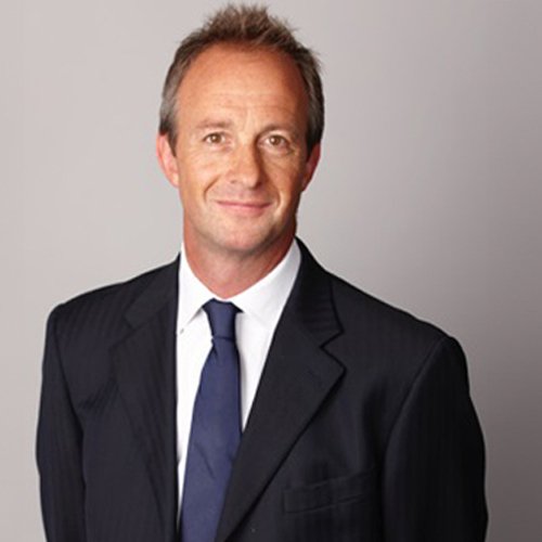 A square head and upper body photo of RCGP CEO Chris Askew wearing a black suit. 