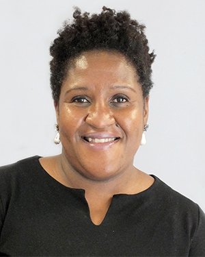 Professor Margaret Ikpoh smiles wearing a black top and pearl earrings. 