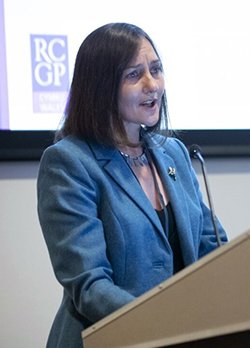 A small card photo of Dr Rowena Christmas speaking at a wooden lectern.