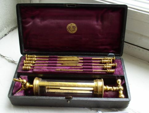 An open, velvet-lined suitcase reveals a collection of metal medical tools. 